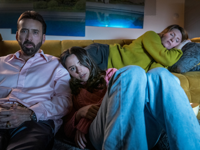 Nicolas Cage (“Nick Cage”, left), Lily Sheen (“Addy”, center) and Sharon Horgan (“Olivia”, right) lay together in the living room as they watch a movie in <em>The Unbearable Weight of Massive Talent</em>. Photo Credit: Katalin Vermes/Lionsgate. The Unbearable Weight of Massive Talent