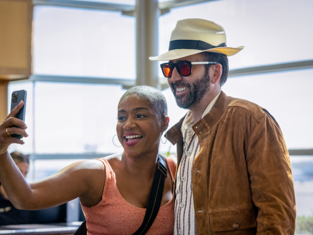 Tiffany Haddish (“Vivian”, left) snaps a selfie with Nicolas Cage (“Nick Cage”, right) while undercover at the airport in <em>The Unbearable Weight of Massive Talent</em>. Photo Credit: Karen Ballard/Lionsgate. The Unbearable Weight of Massive Talent